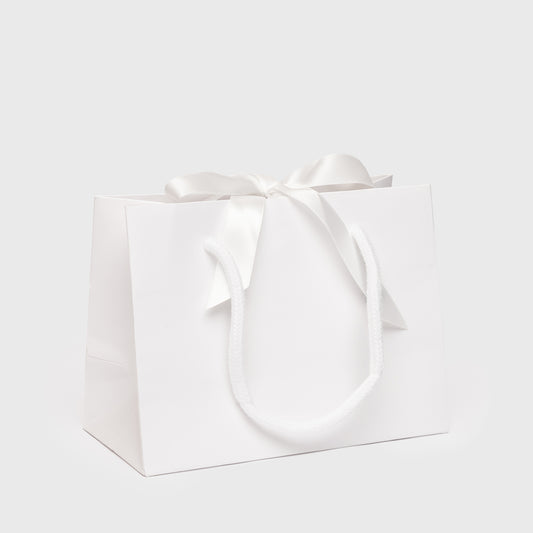 White gift bag with a bow on a light gray background