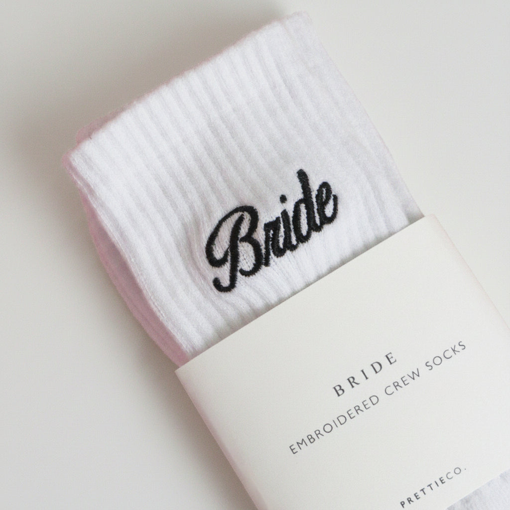 White socks with 'Bride' embroidery in packaging on a pink background