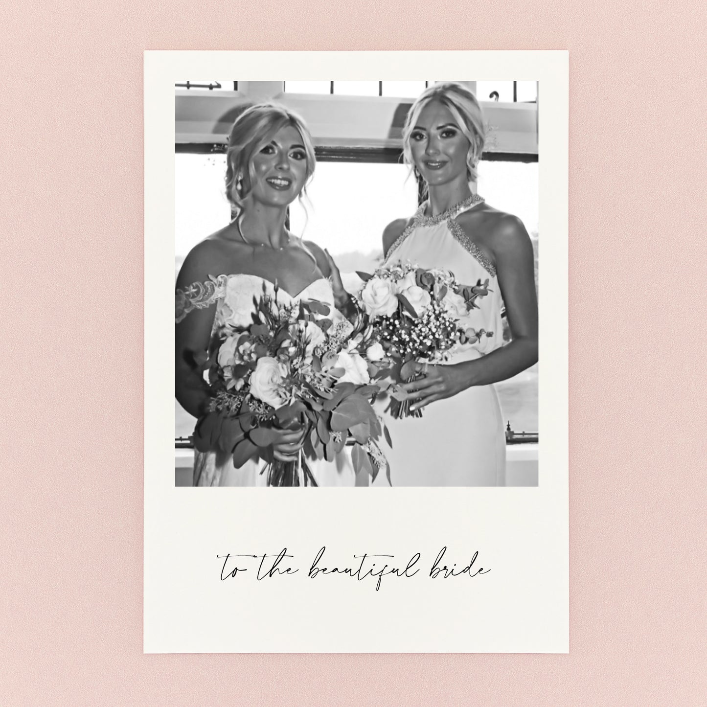 White card with Two women holding bouquets with text 'to the beautiful bride' photographed on a pink background