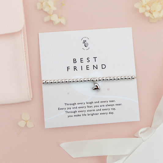 Silver beaded bracelet with a heart charm for best friends, displayed on a custom card with a heartfelt friendship message, set against a soft pink background.