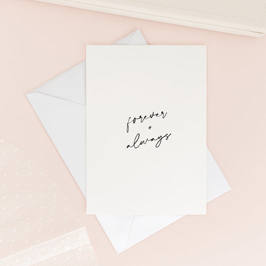 Greeting card with 'forever + always' text on a pink surface