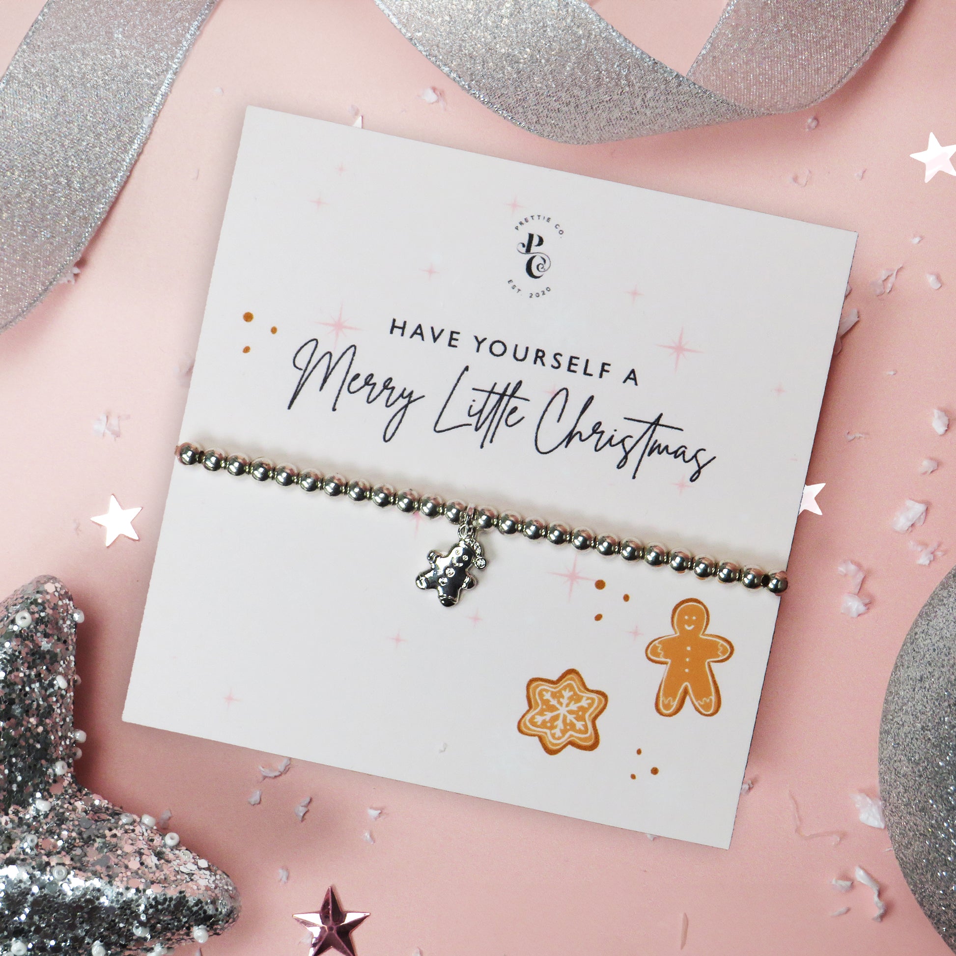 Silver-plated gingerbread man charm bracelet on a festive "Merry Little Christmas" card with gingerbread illustrations, perfect for holiday gifts and stocking fillers.