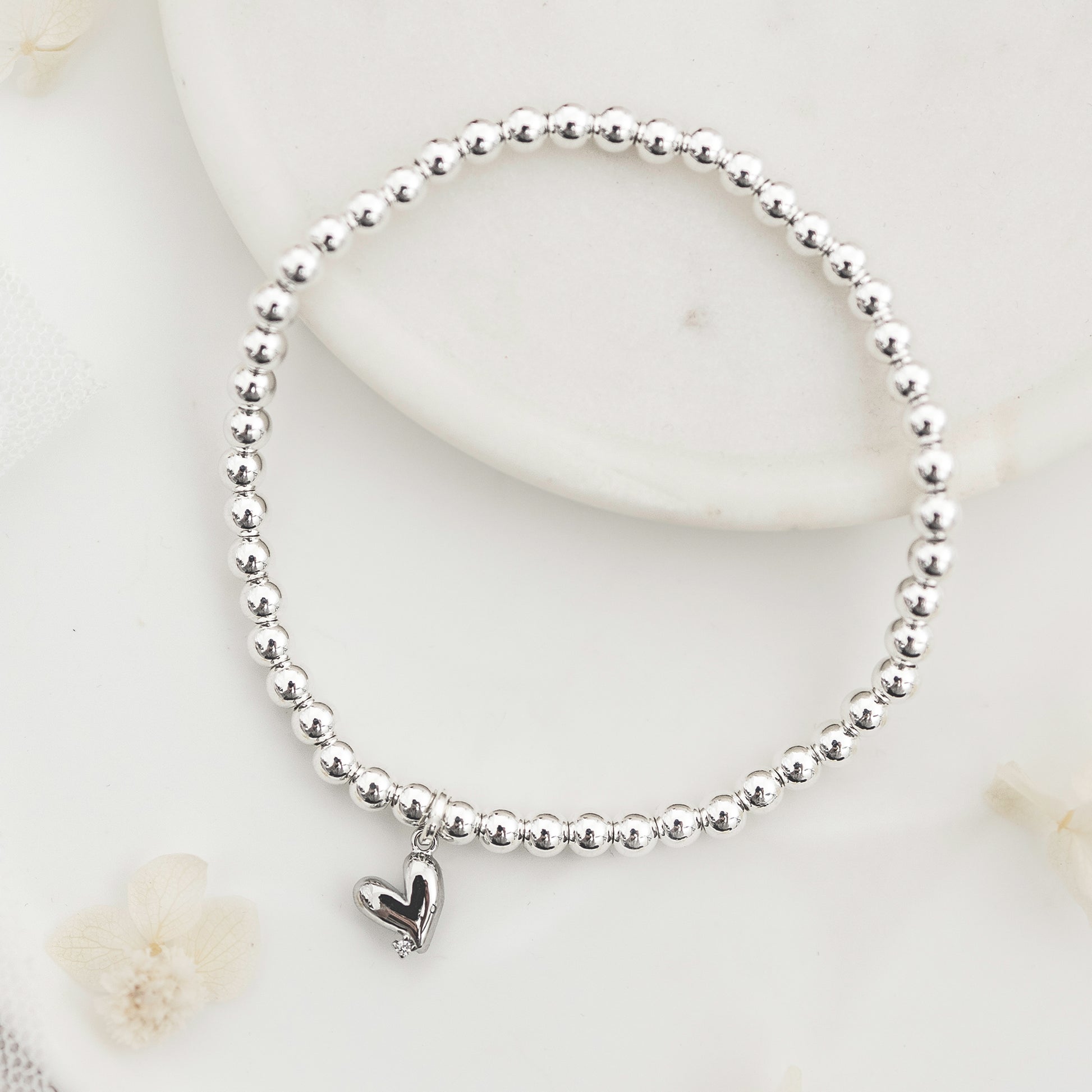 Silver beaded bracelet with a heart charm.