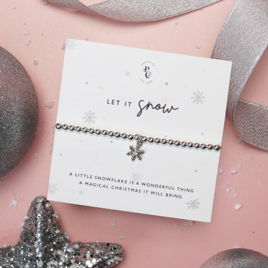 Silver-plated snowflake charm bracelet on a festive "Let it Snow" card with delicate snowflake illustrations, perfect for Christmas gifts and stocking fillers.