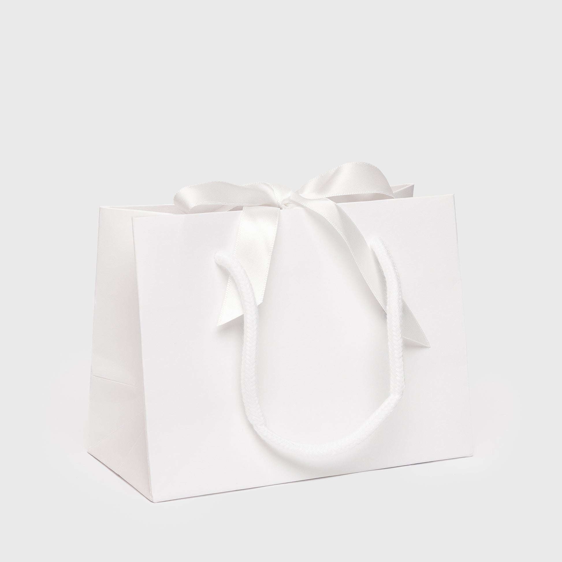 White gift bag with a bow on a light gray background