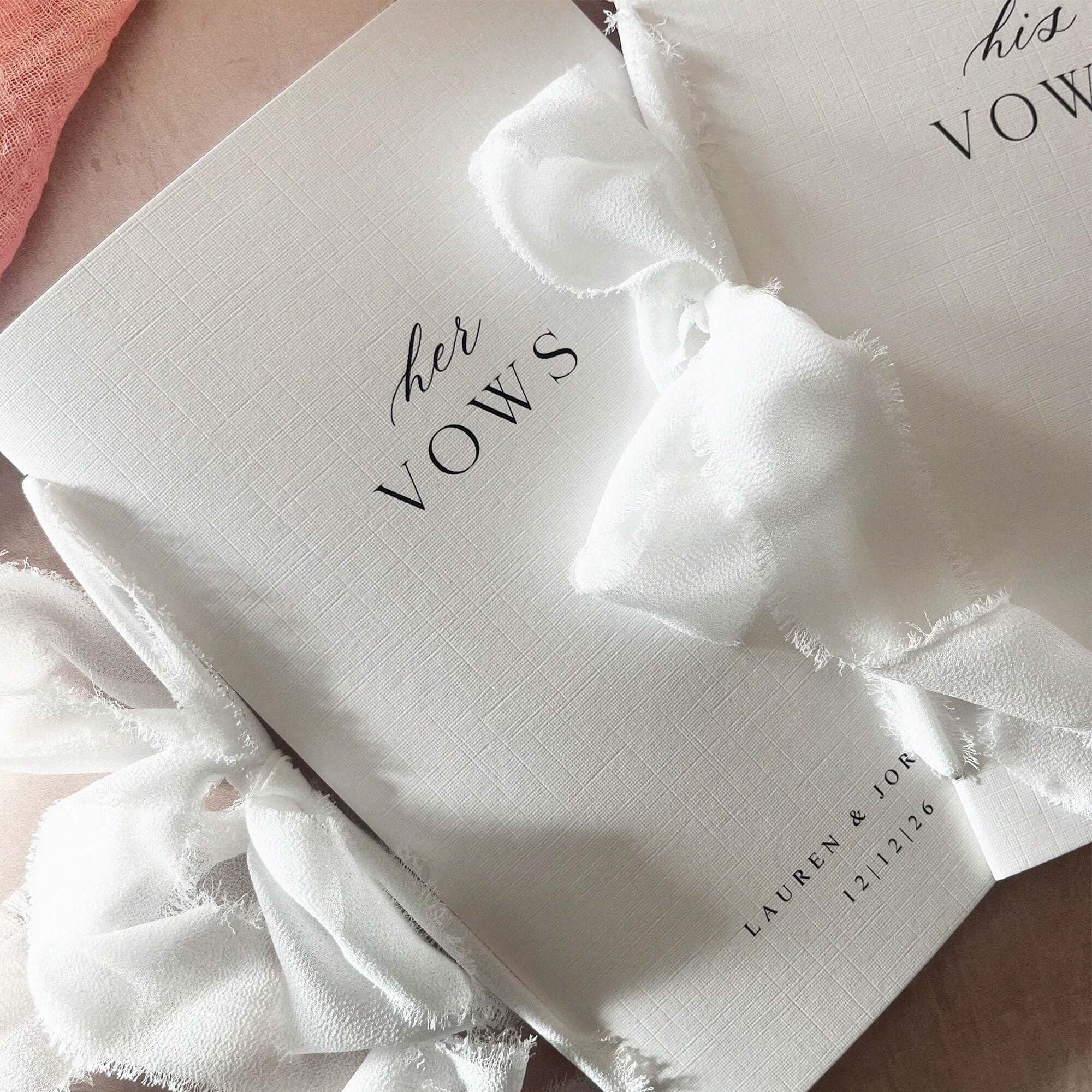White wedding vow book with a bow and personalised text on a light background